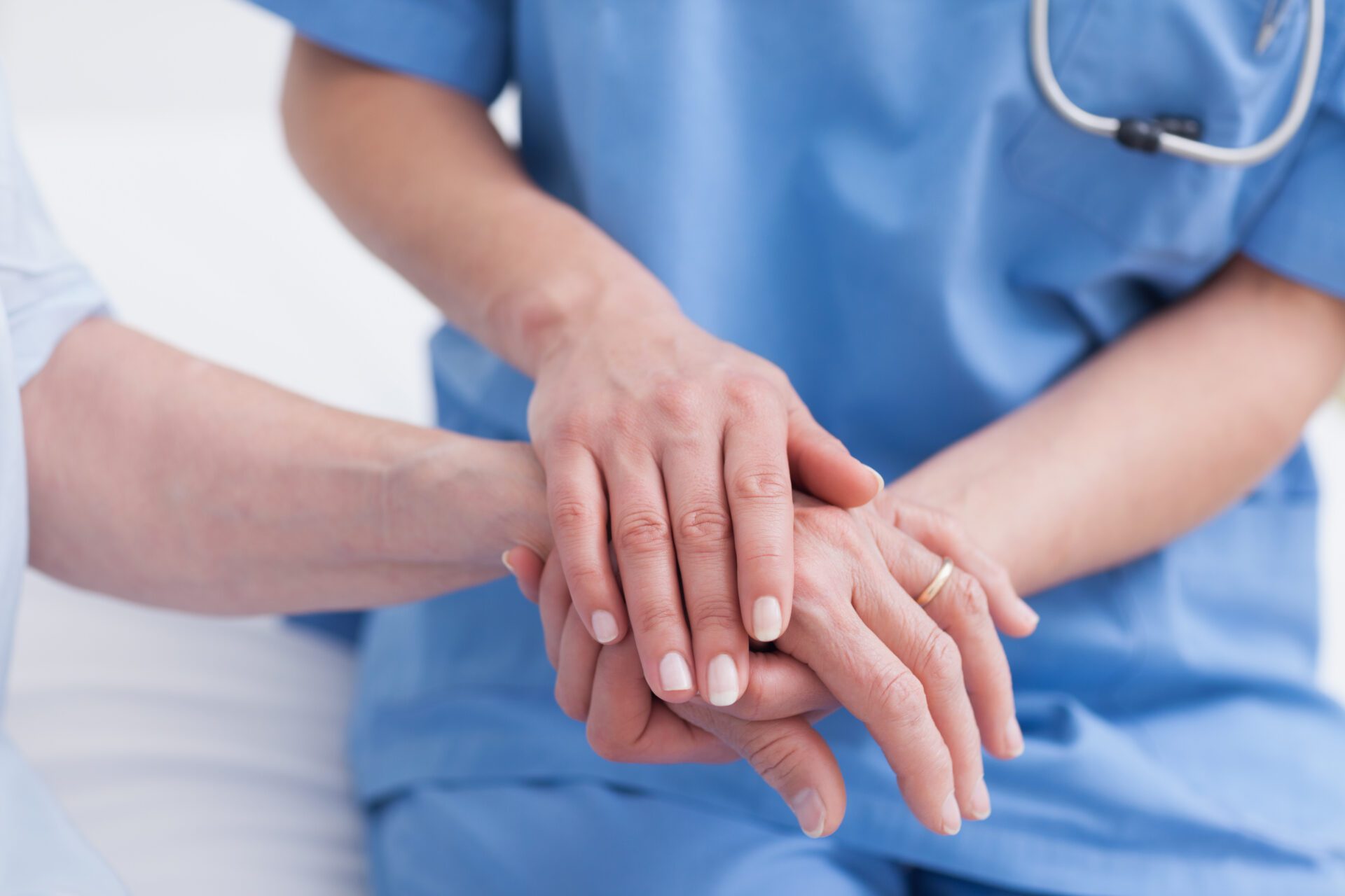 Close up of a nurse touching hand of a patient in hospital ward